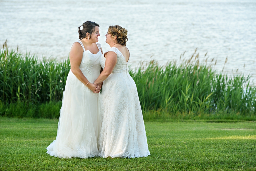 A gay couple hold hands along the water after their wedding.
